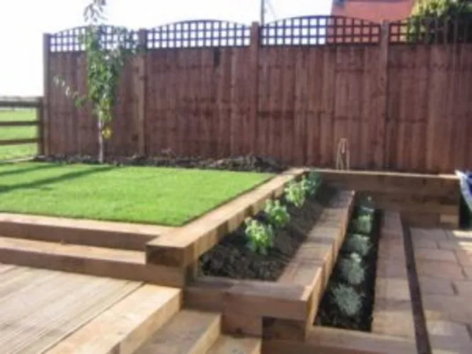 Timber sleepers used as raised garden edging in a backyard landscaping project.