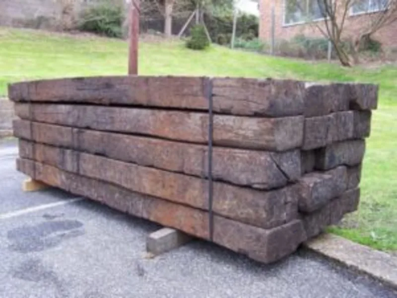 Stacked reclaimed timber sleepers tied together with metal straps.
