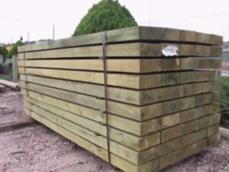 Stack of new timber sleepers bundled with metal straps on a construction site.