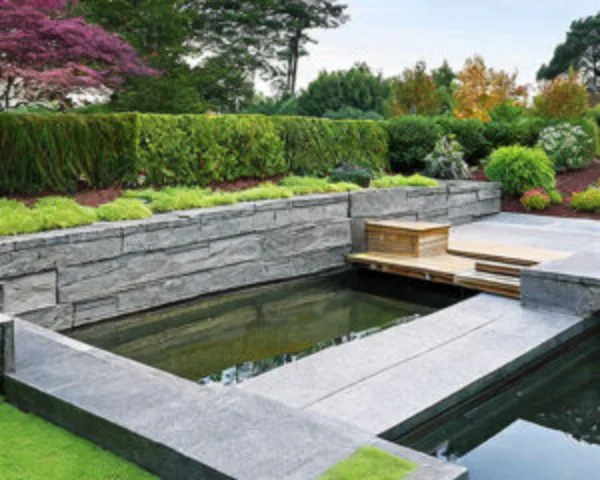 Stone retaining wall surrounding a landscaped garden and small water feature.